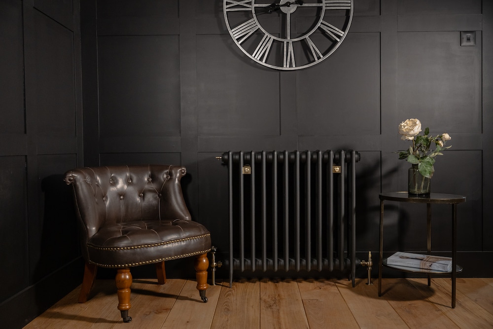 Victorian Cast Iron Radiator alongside a leather chair and side table with flowers.
