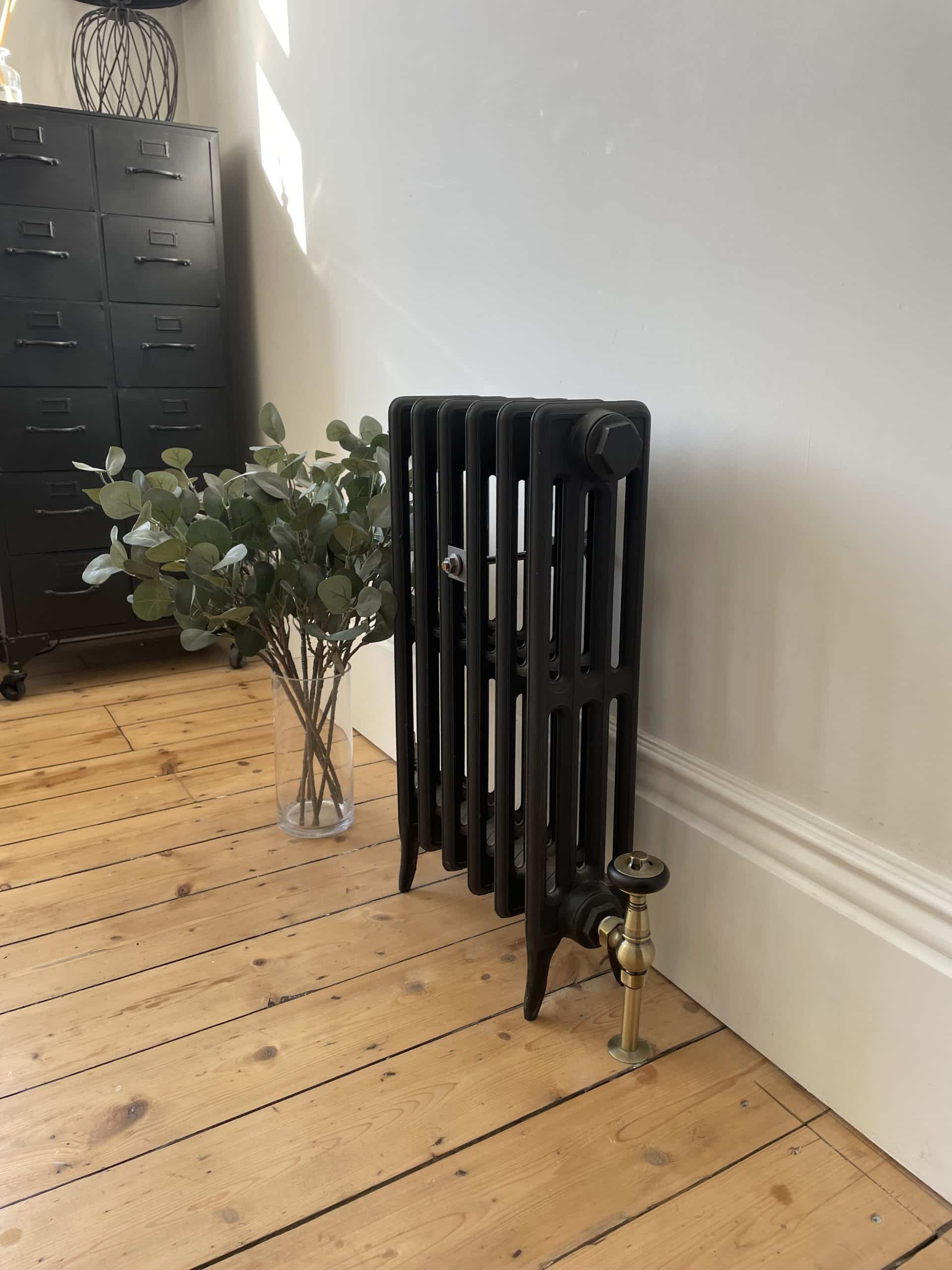 Vintage cast iron radiator beside a vase of flowers.
