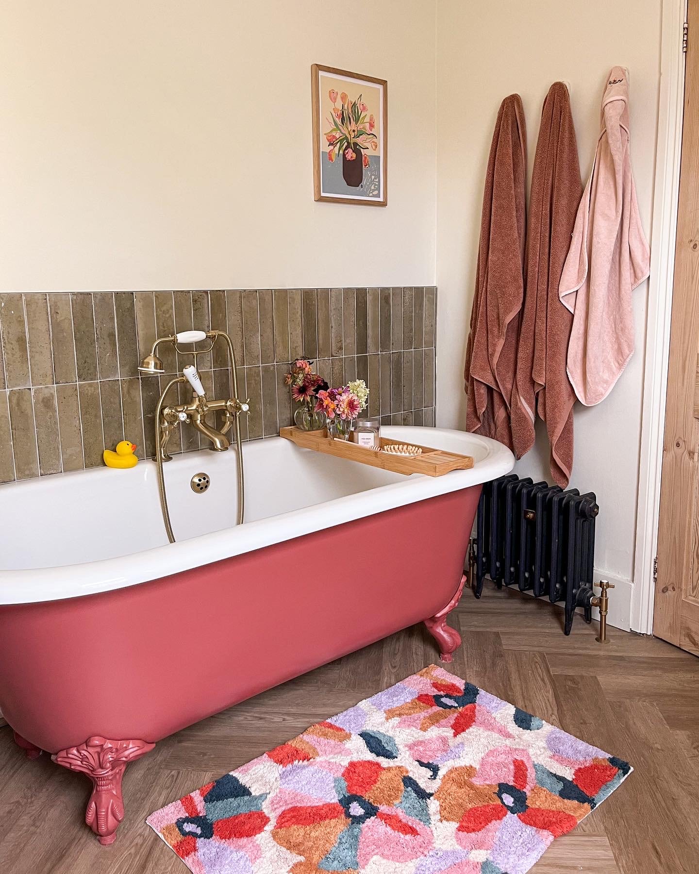 Stylish bathroom with pink bathtub and black cast iron radiator.