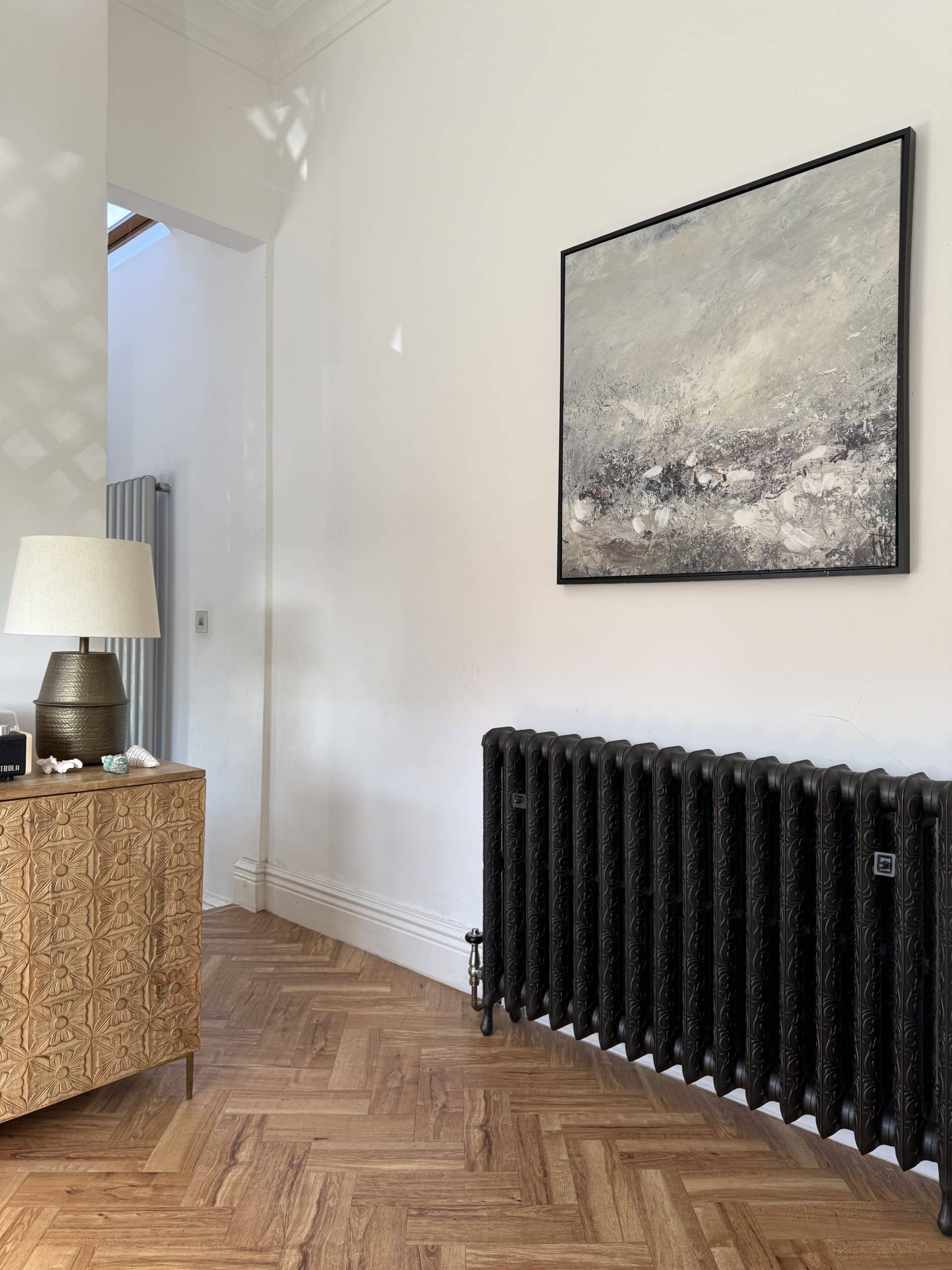 Modern room with cast iron radiator and artwork.